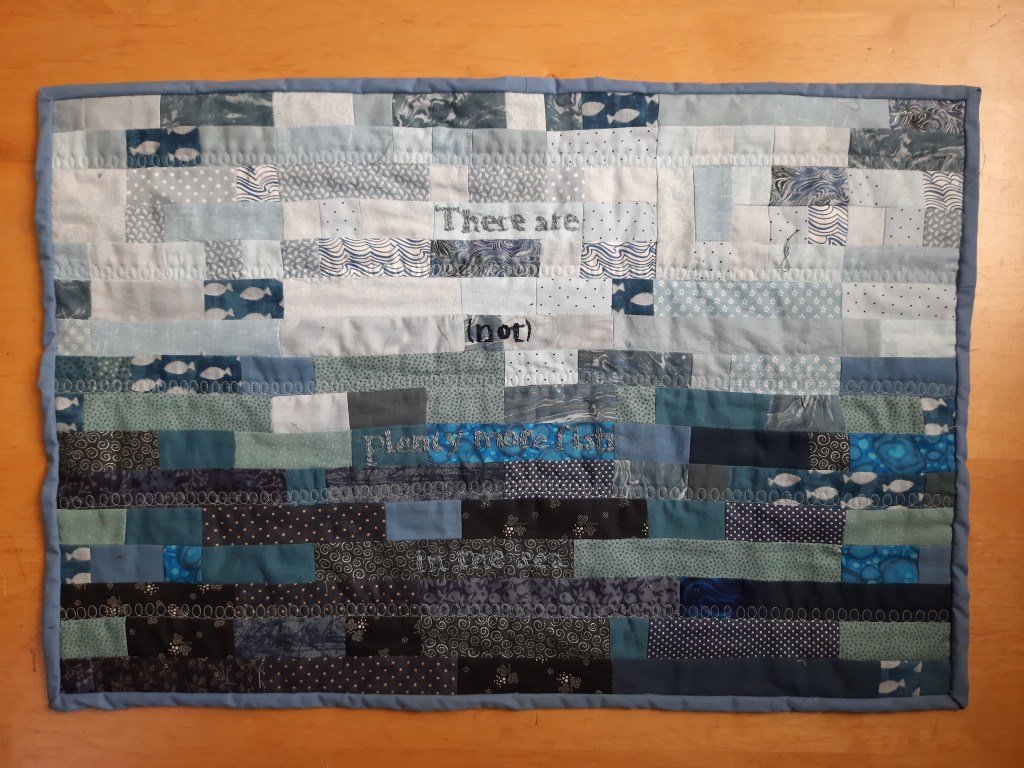 'There are {not} plenty more fish in the sea' by Amanda Jane Ogden, small quilt composed on blue blocks, a few with fish in and the wor