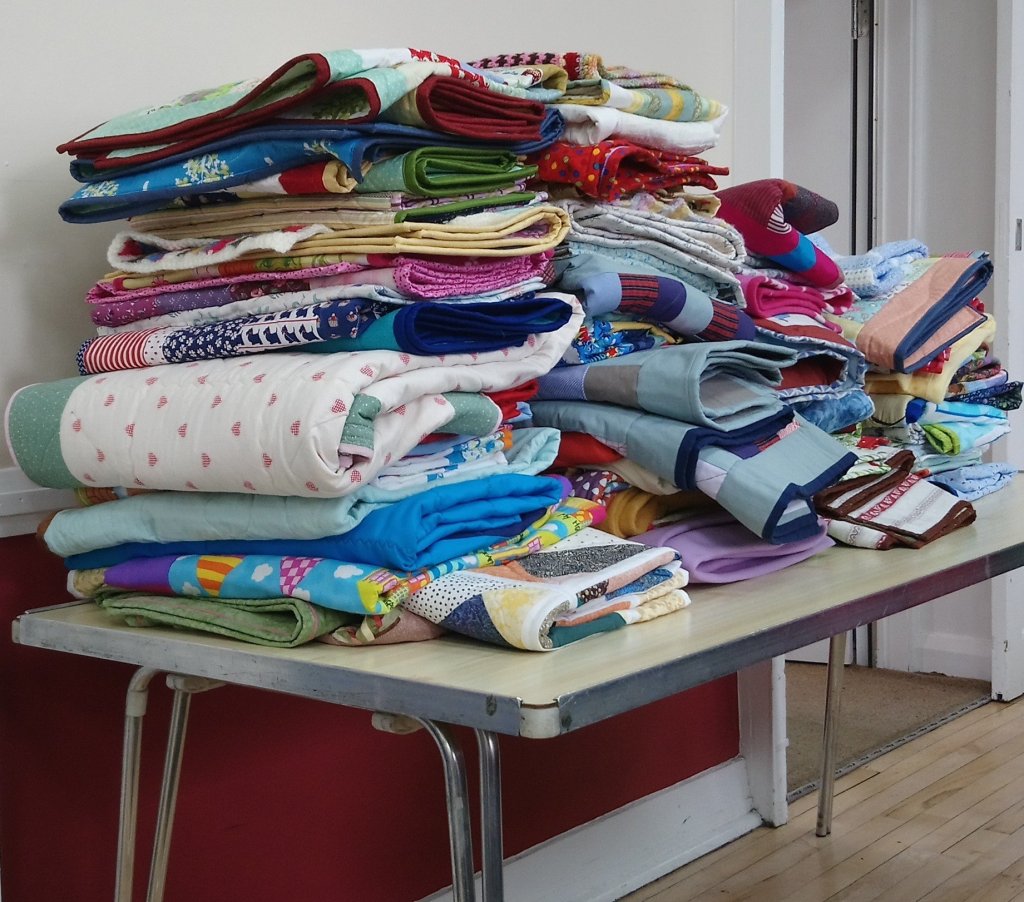 a pile of quilts on a table, all made to give away
