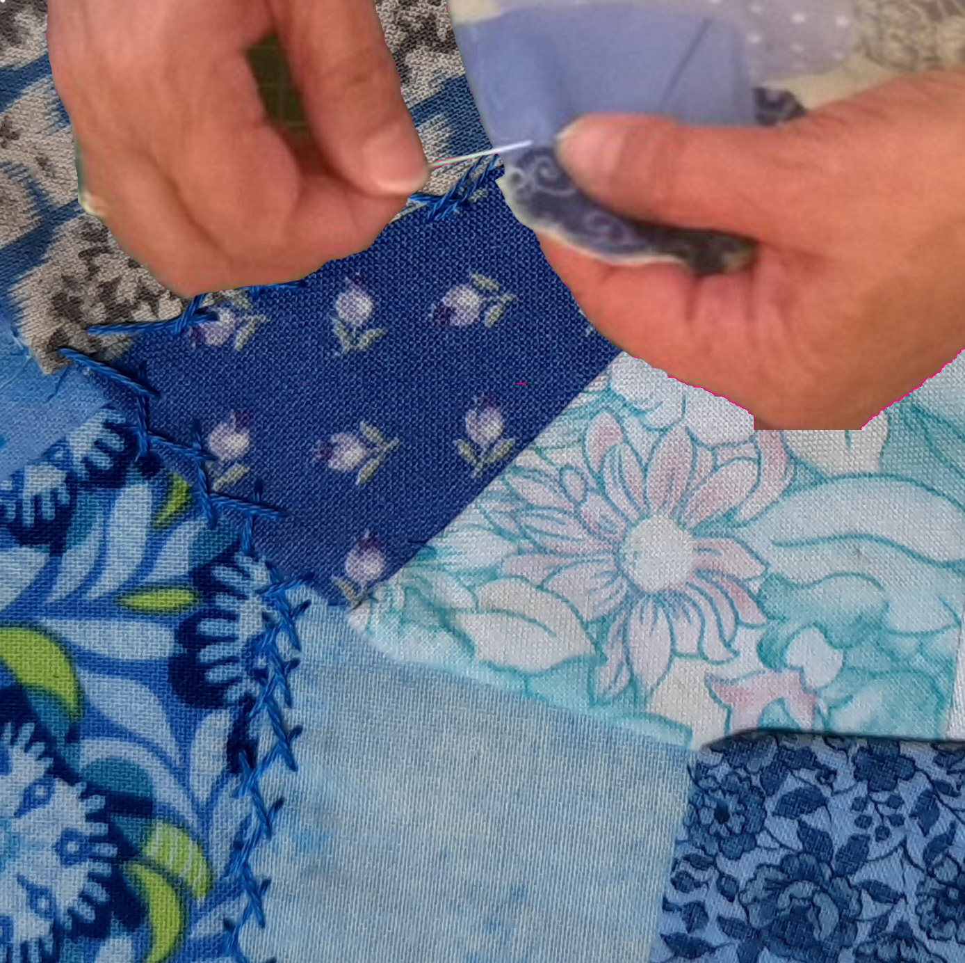 Hands holding a needle and embroidery thread, the person is working on a piece of crazy patchwork