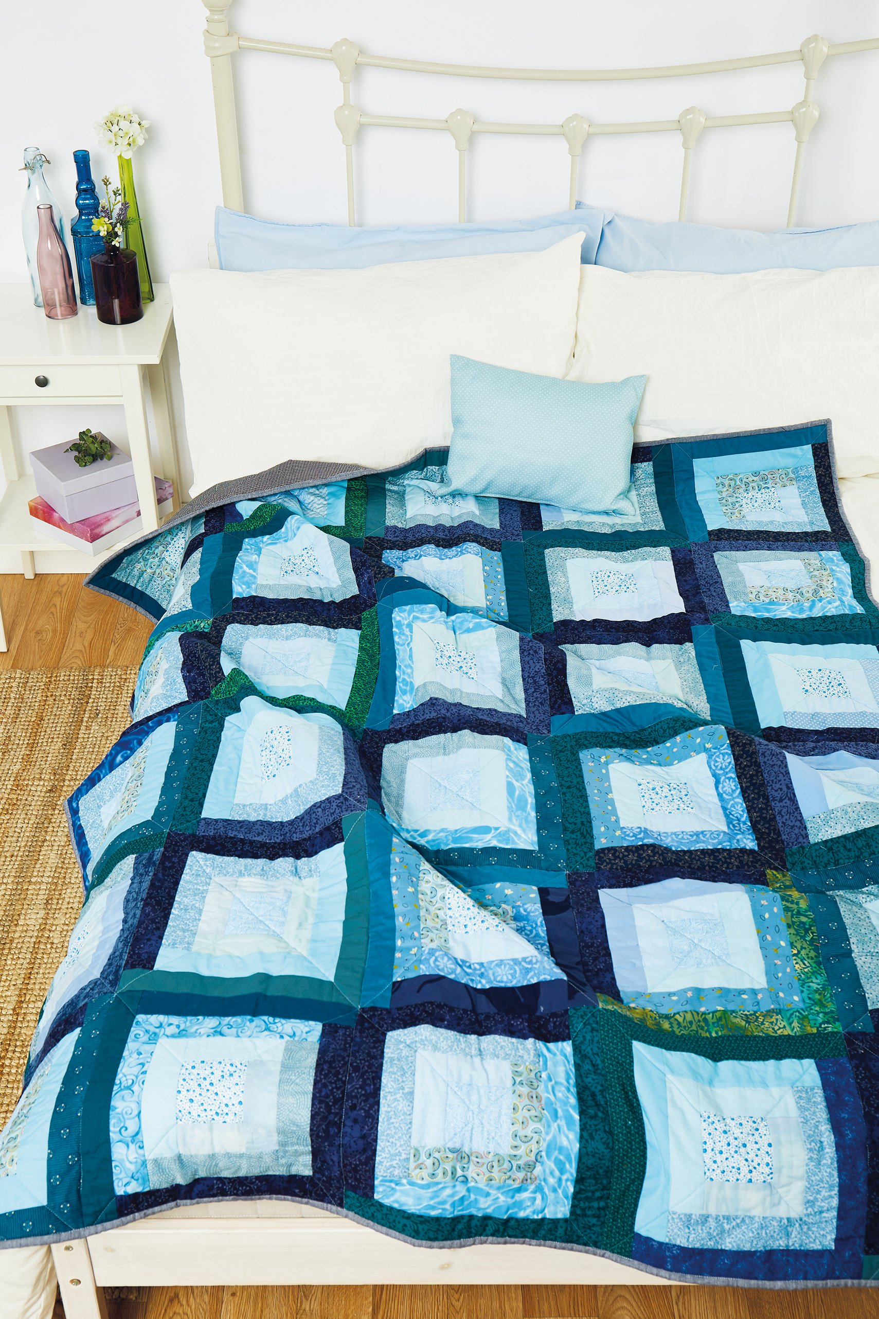 A blue and green quilt using a modern version of log cabin blocks
