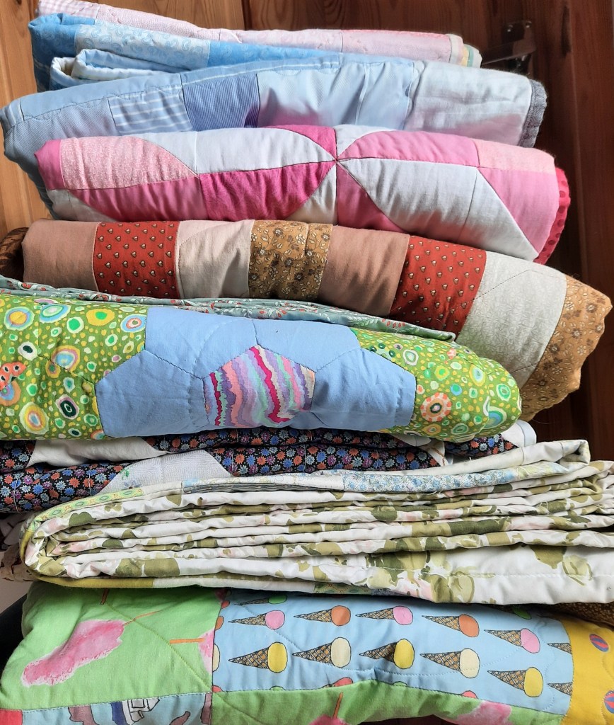 A pile of quilts on a chair, all made by Amanda Jane Ogden
