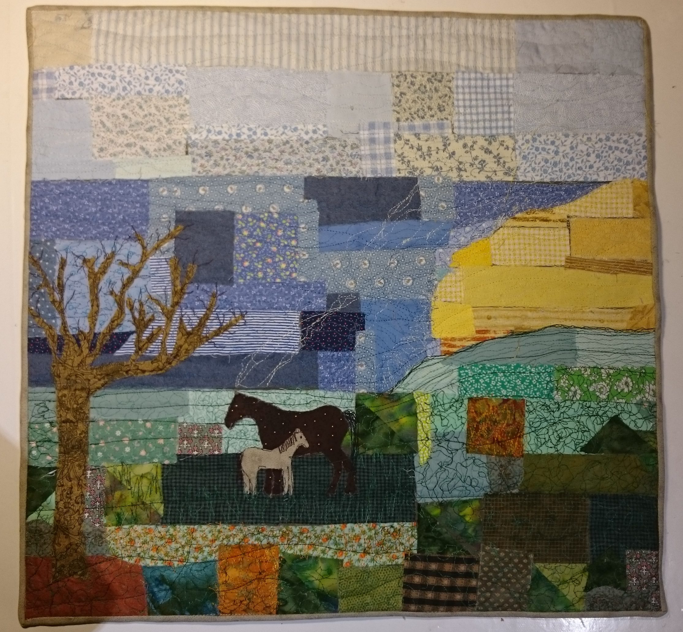 A fabric collage of sea, sky, the moors and two ponies under a tree