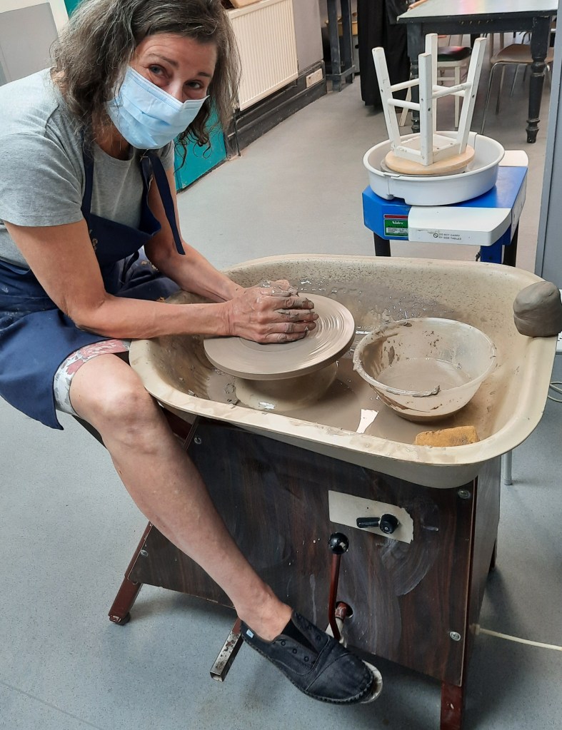 learning to centre a lump of clay on a potter's wheel