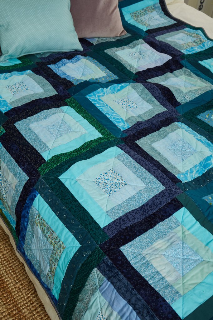 Detail of a blue and green quilt by Amanda Jane Ogden, using a modern version of log cabin blocks
