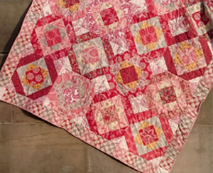 'Terrazzo' a quilt commissioned by and Italian couple for their friend; the quilt has the look of a mosaic floor in reds, pinks, yellows and cream