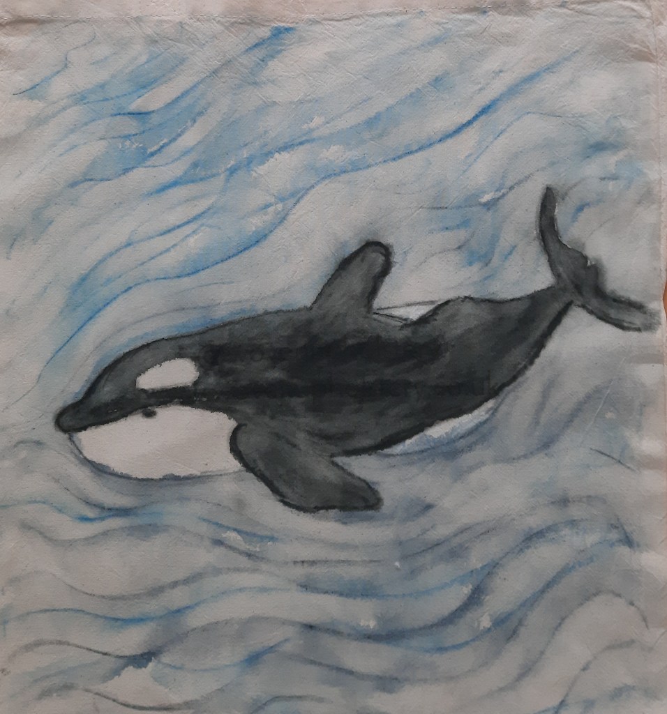 an orca swimming in the sea, created using Inktense fabric pencils