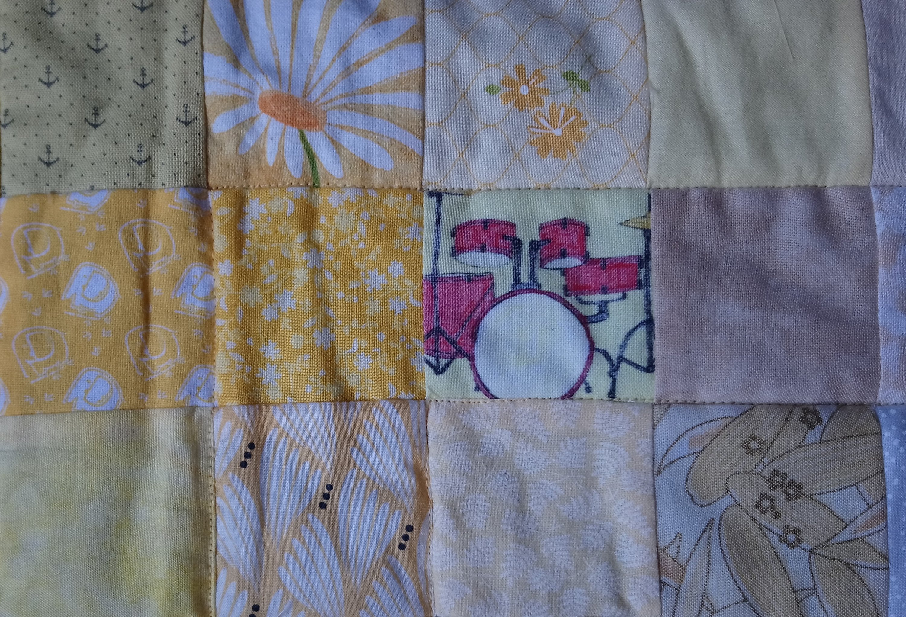 A quilt of yellow squares including Drums fabric by Amanda Jane Textiles
