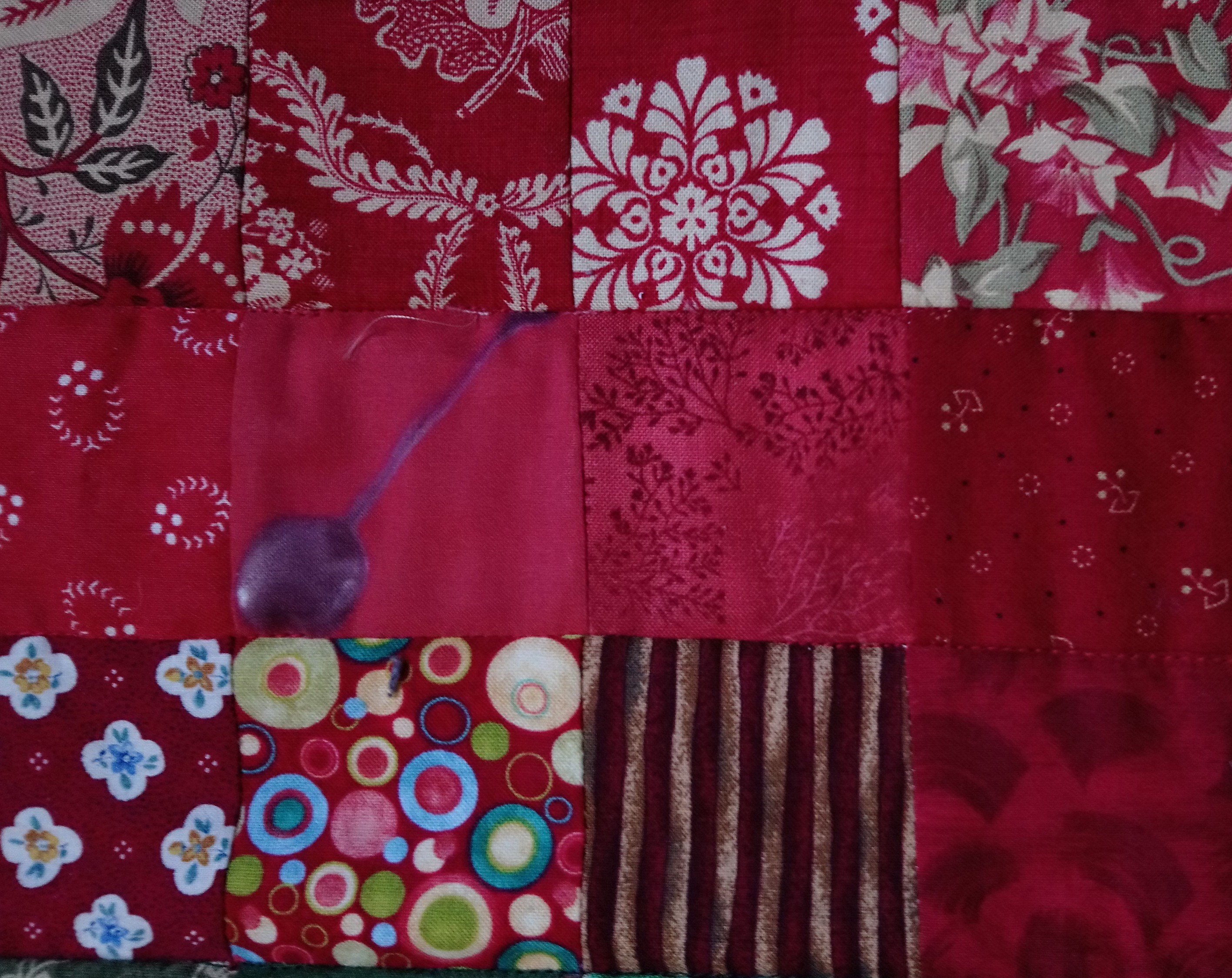 A quilt of red squares including Dancing Spoons fabric by Amanda Jane Textiles