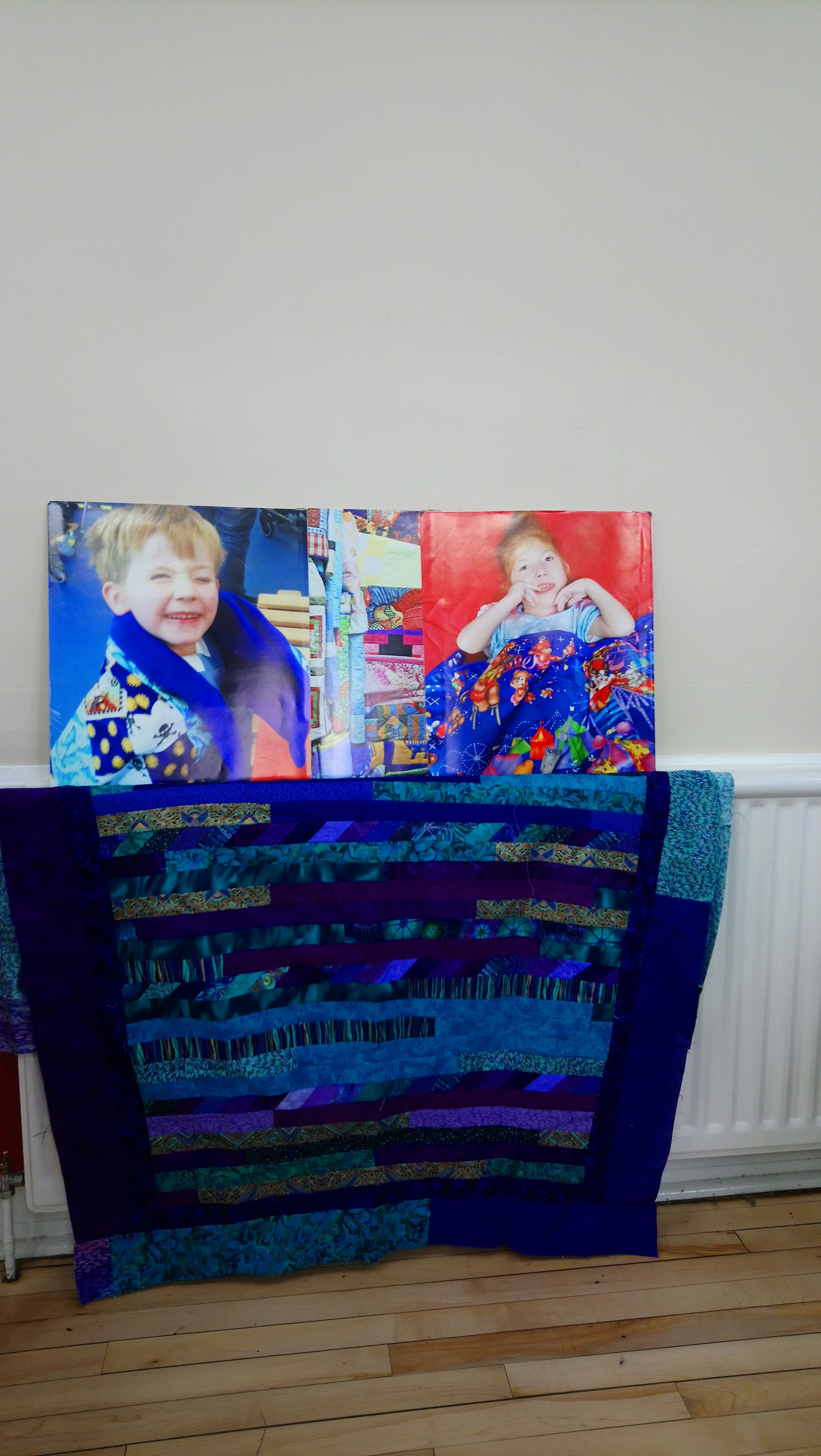 a quilt with photos of recipients of Linus Quilts behind