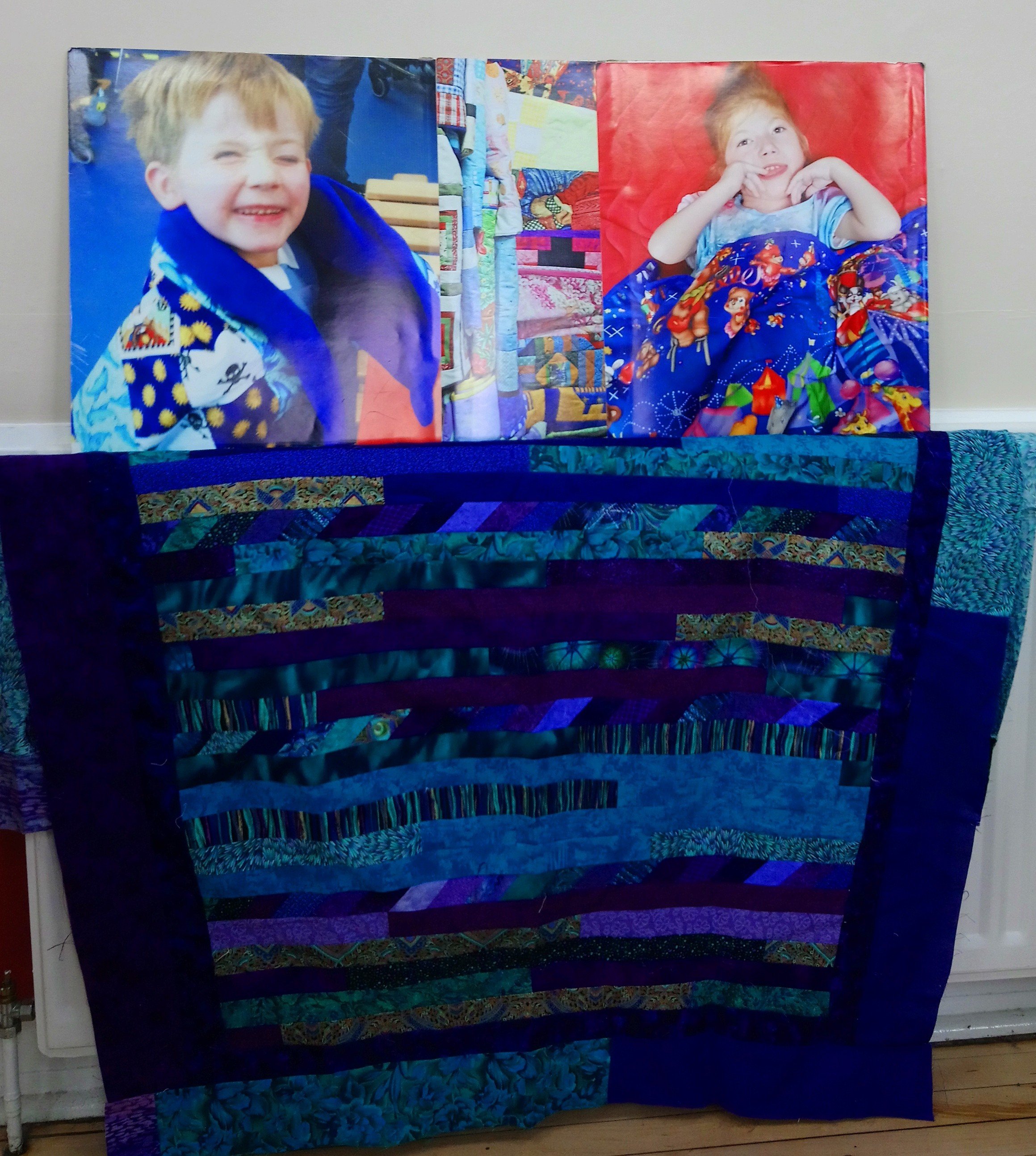 a quilt top with photos of recipients of Linus Quilts behind