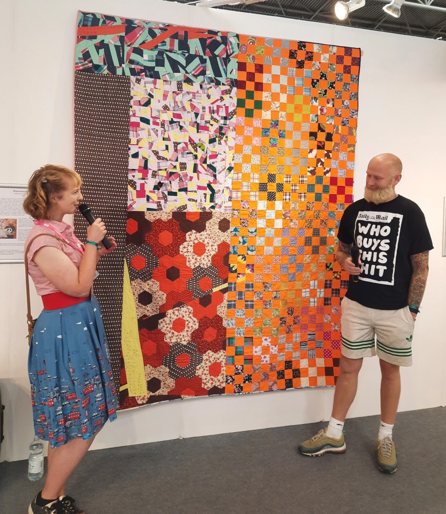 Chris English on The Quilters' Guild stand at the Festival of Quilts 2023, with Heather Audin