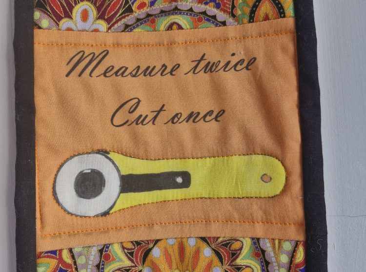 'Measure twice, cut once' motif on a wall-hanging