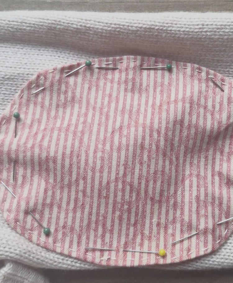 The patch with hand-stitched edge pinned to the cardigan
