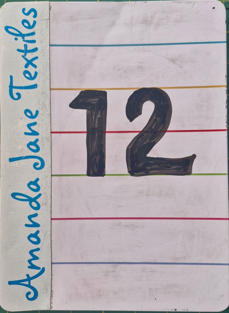 The number 12 written on a small whiteboard, photo by Amanda Jane Ogden